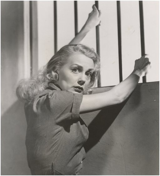 actress june havoc gripping the iron bars on her prison cell window