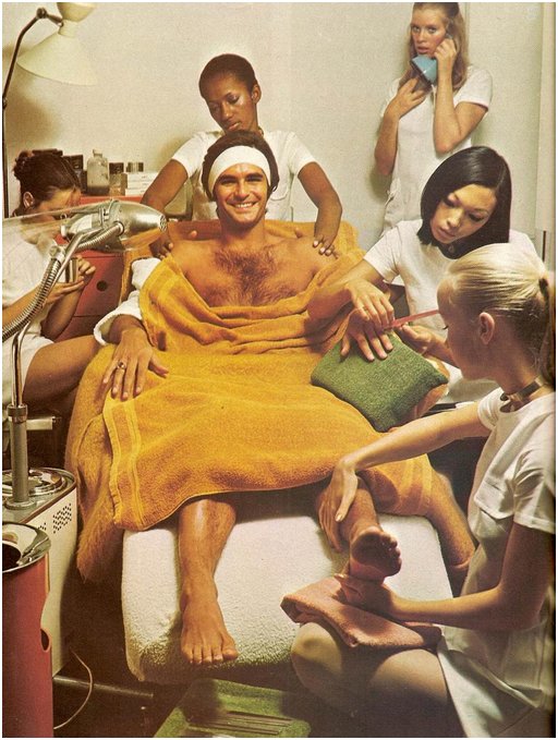 smug man surrounded by five beautiful young women who are pampering him with manicure and massage